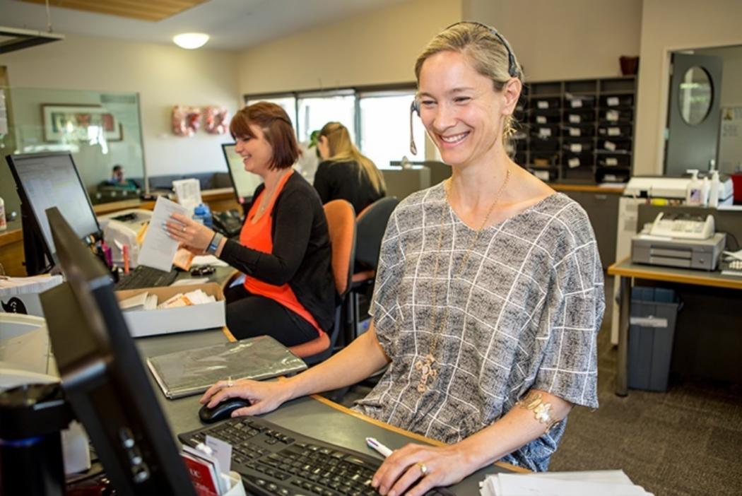 Consultant smiling and looking into computer at the UC Health Centre